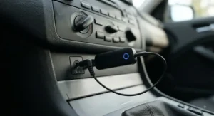 Close-up of a Bluetooth car adapter connected to an auxiliary port, enabling hands-free calls in older car models.