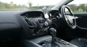 Plug-and-play bluetooth fm transmitter for car sitting neatly in a British vehicle interior.