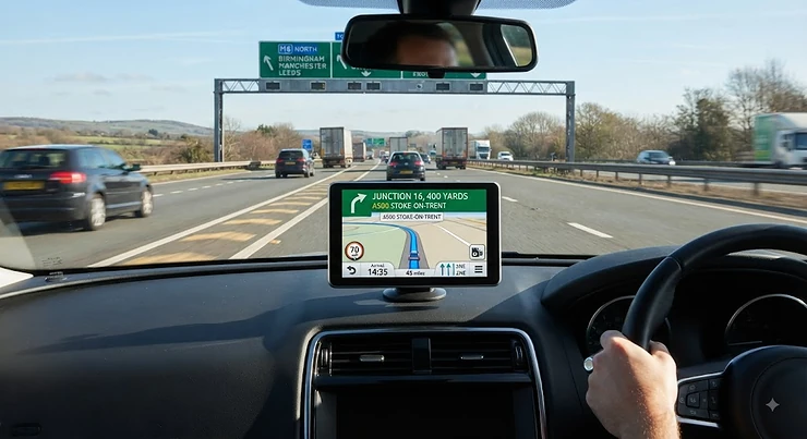 Modern sat nav for roads displaying a clear route on a busy British motorway.