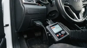 A compact OBD2 scanner plugged into a car dashboard port, ideal for finding cheap fault codes under £30.